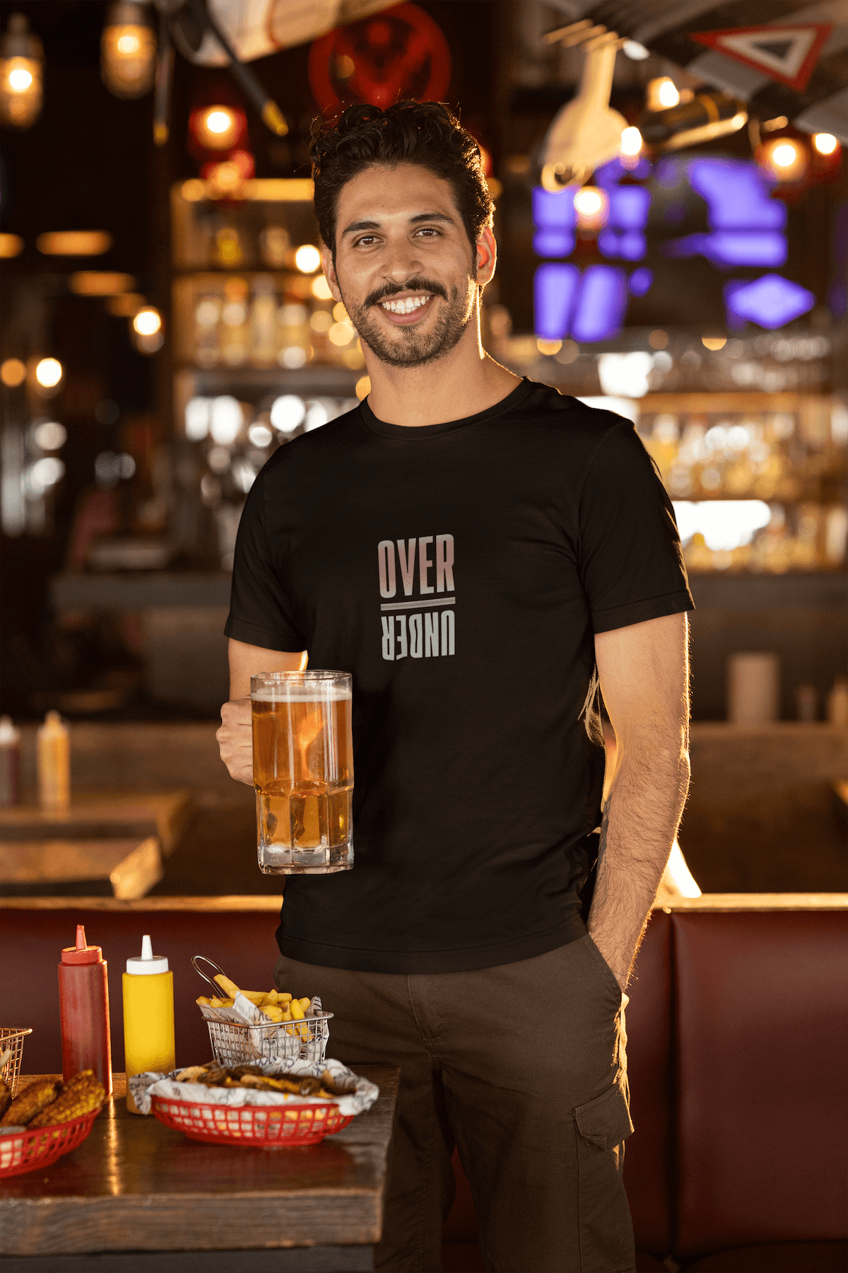 Dark haired man holding a beer and wearing a Over/Under Odds on Outfitters t-shirt